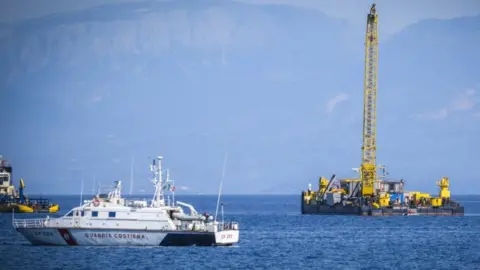 EPA A crane and a coastguard boat in the sea where the Bayesian sank