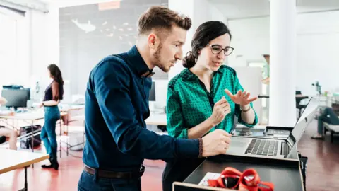 Getty Images A man and a woman in an office looking at a laptop computer