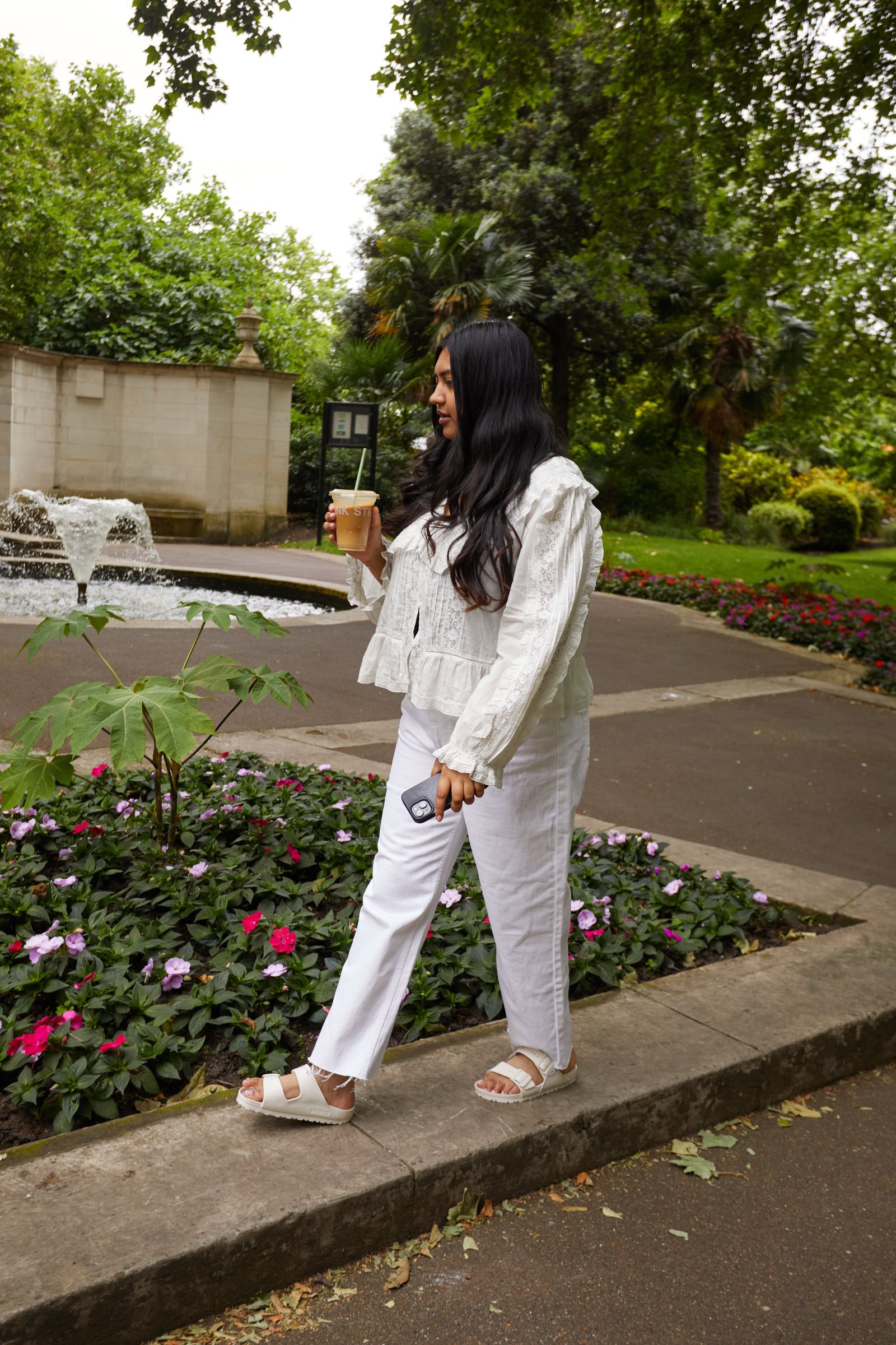 Image may contain Clothing Pants Plant Potted Plant Person Standing Walking Cup Footwear Sandal Teen and Grass