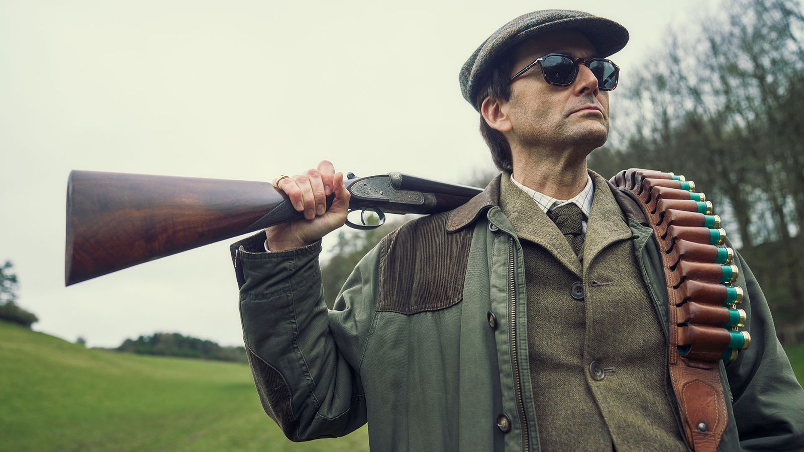 Image may contain David Tennant Weapon Gun Firearm Rifle Adult Person Accessories Formal Wear Tie and Glasses