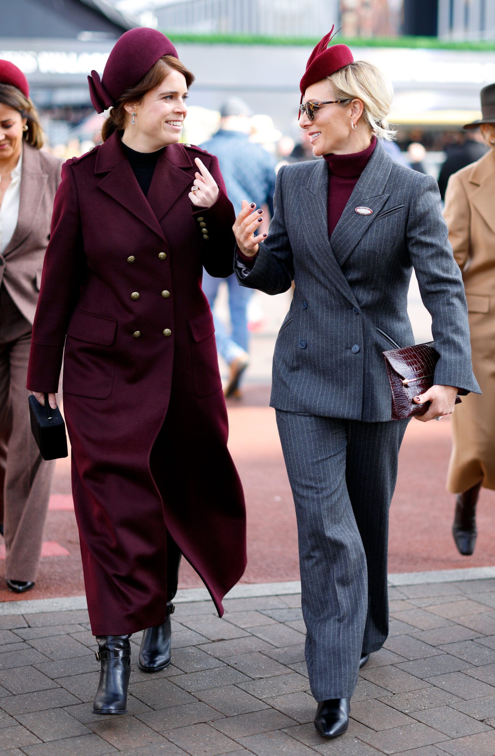 Princess Eugenie and Zara Tindall walking next to each other in suits and long coats