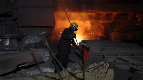 Getty Images Steel worker in front of a furnace in the UK