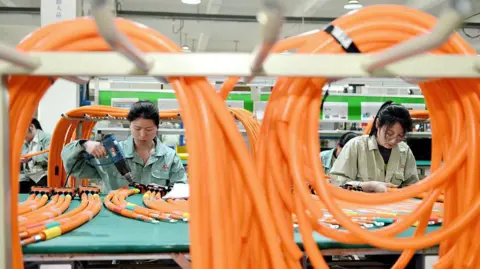Getty Images Workers manufacture high-voltage wiring harness products for new energy vehicles in the workshop in Nantong City, Jiangsu Province, China, on May 13, 2025.