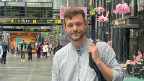 Maddy Savage Oskar Damkjaer holding a backpack at the station