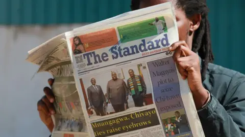 A man reading The Standard newspaper from early May with a photo of Wicknell Chivayo standing between Kenya's President William Ruto (L) and Zimbabwe's President Emmerson Mnangagwa (R)