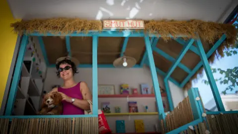 Caroline, 29, and her dog, attend the opening of a romance genre bookshop in west London