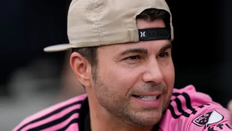 Getty Images Mark Rober in a pink football shirt and backwards baseball cap