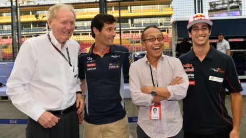 Getty Images Four men standing side by side in front of an F1 race track. From left to right is Ron Walker, Mark Webber, Ong Beng Seng and Daniel Ricciardo