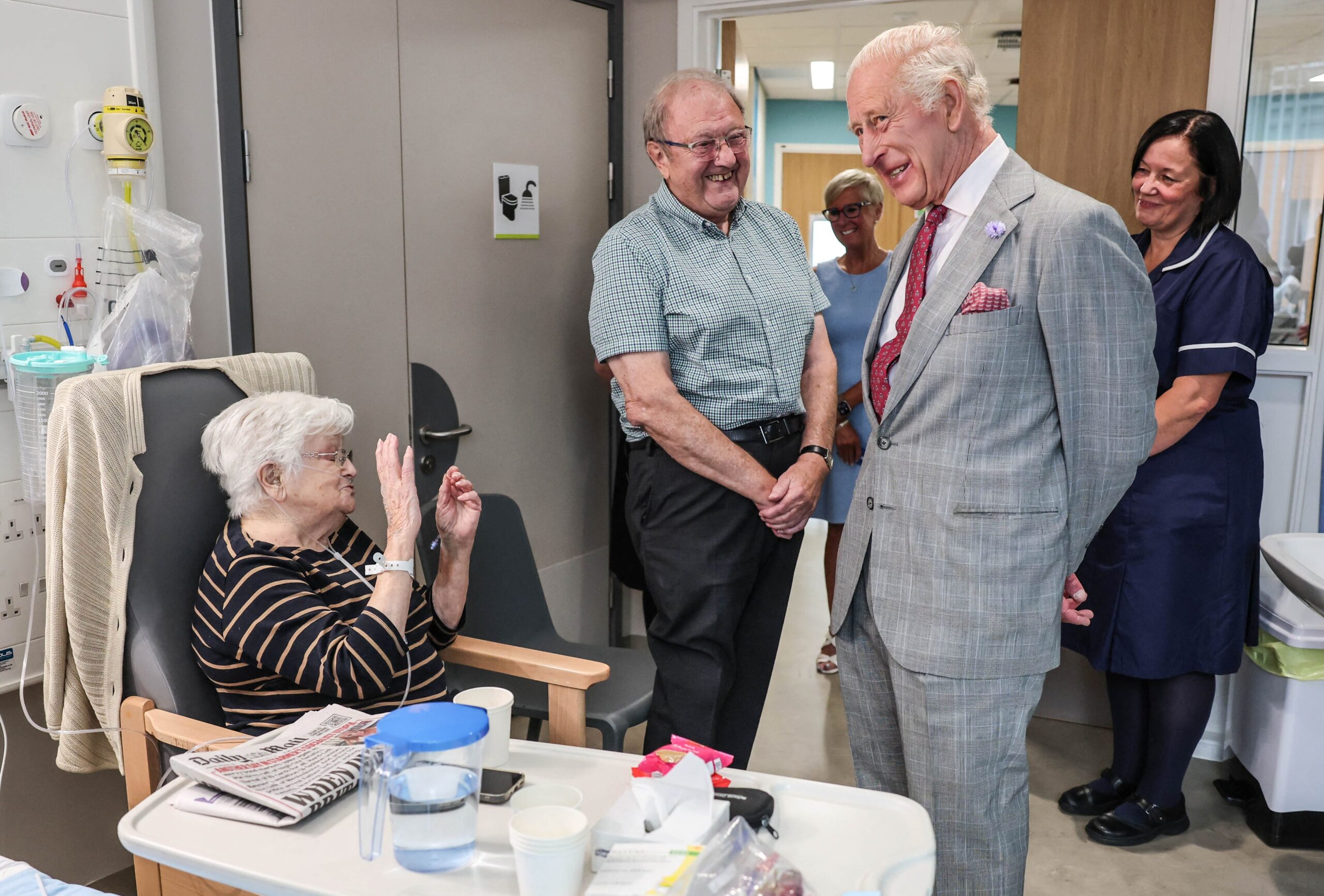 King Charles III visiting a patient in a hospital ward.