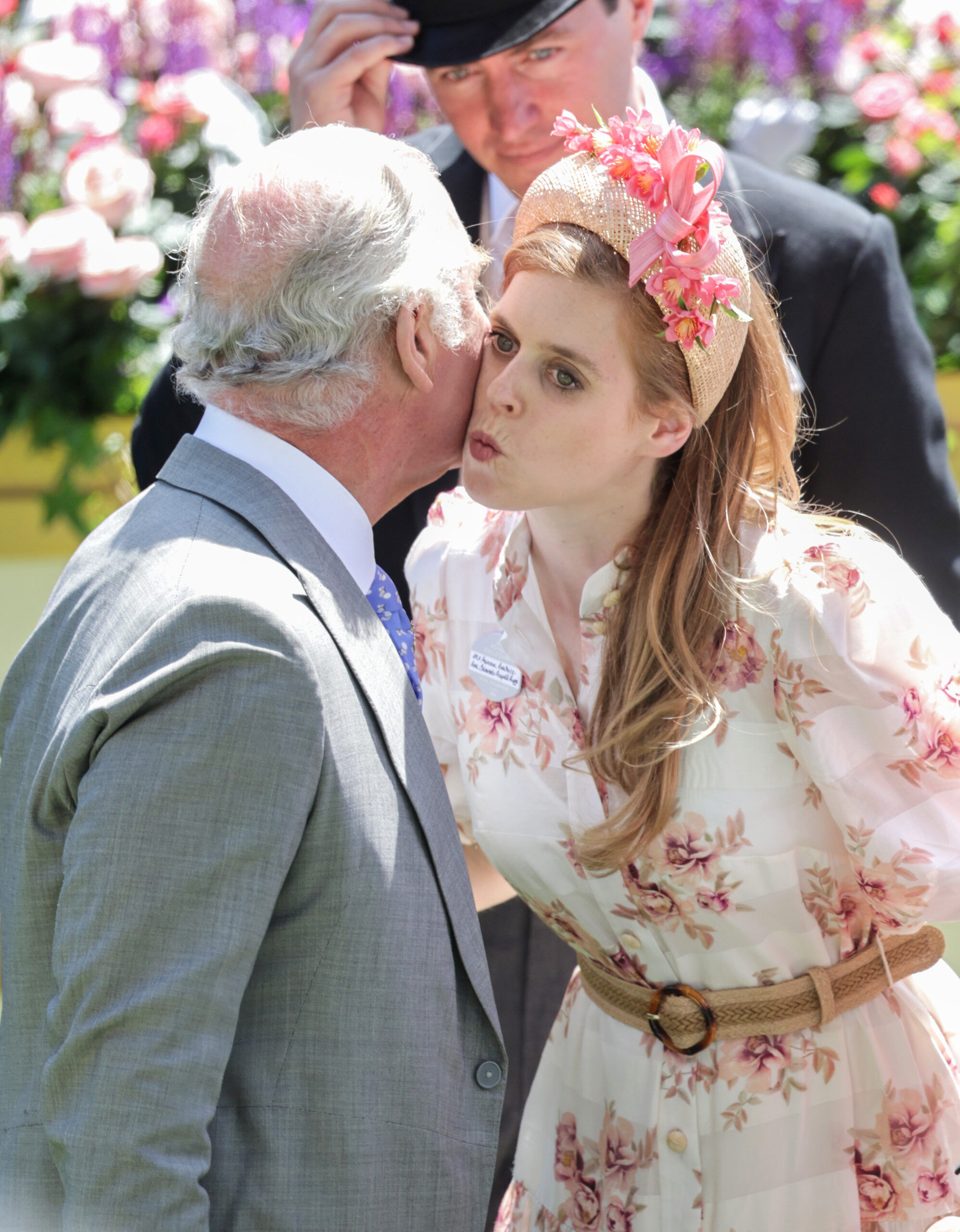 Princess Beatrice wearing a pink flowered dress kissing King Charles on the cheek