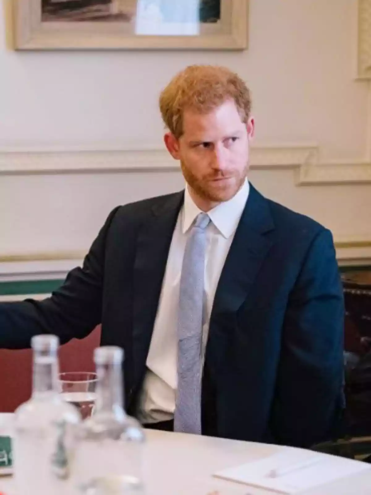 Red-haired man with a beard and a dark suit sitting at a table during a meeting