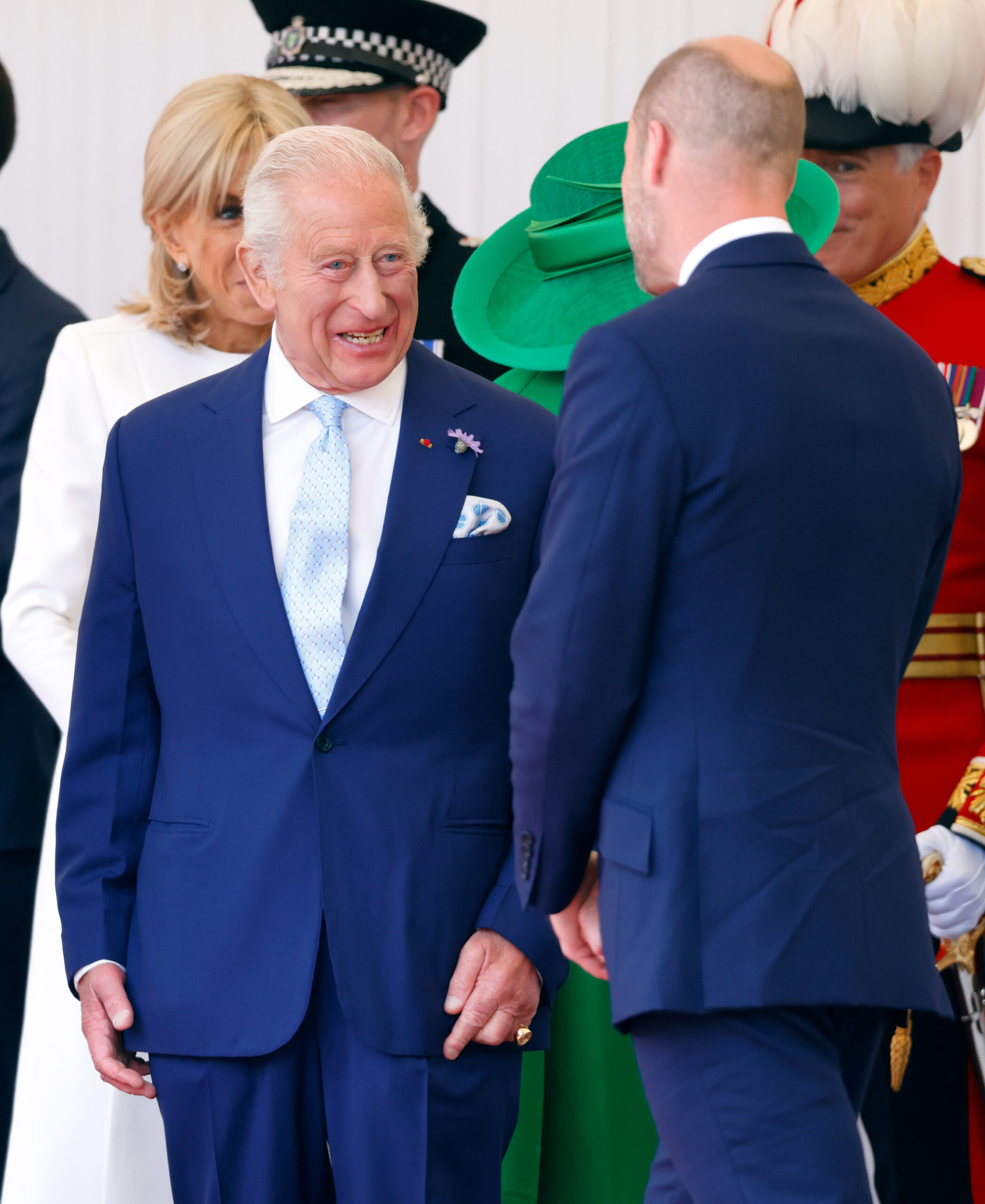 King Charles and Prince William wearing blue suits and talking to each other in front of a group of people