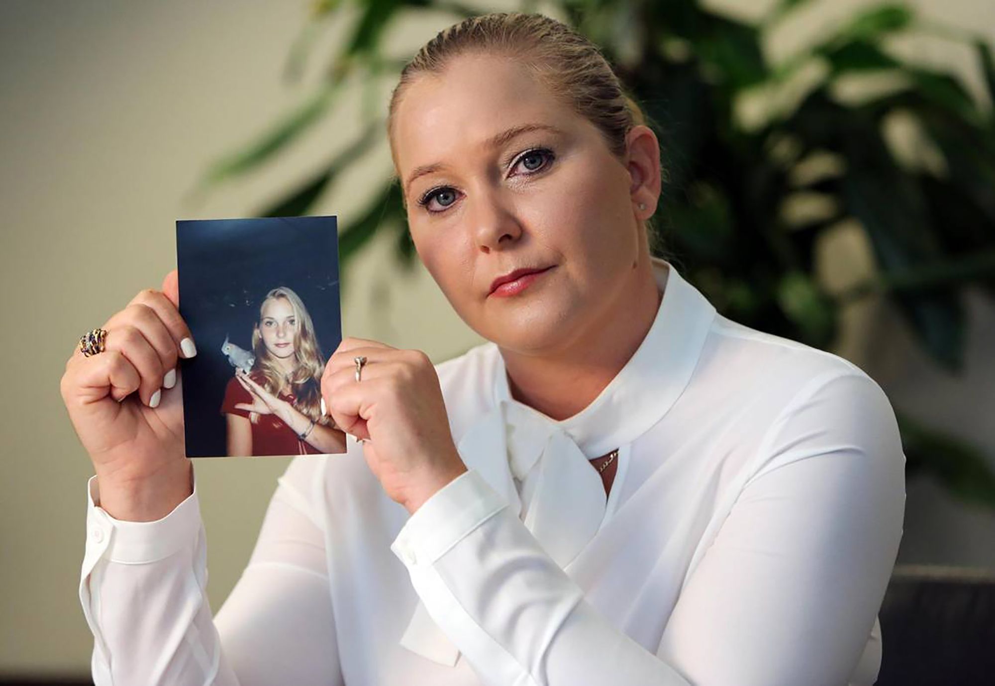 Virginia Roberts Giuffre holding a photo of herself as a teenager.