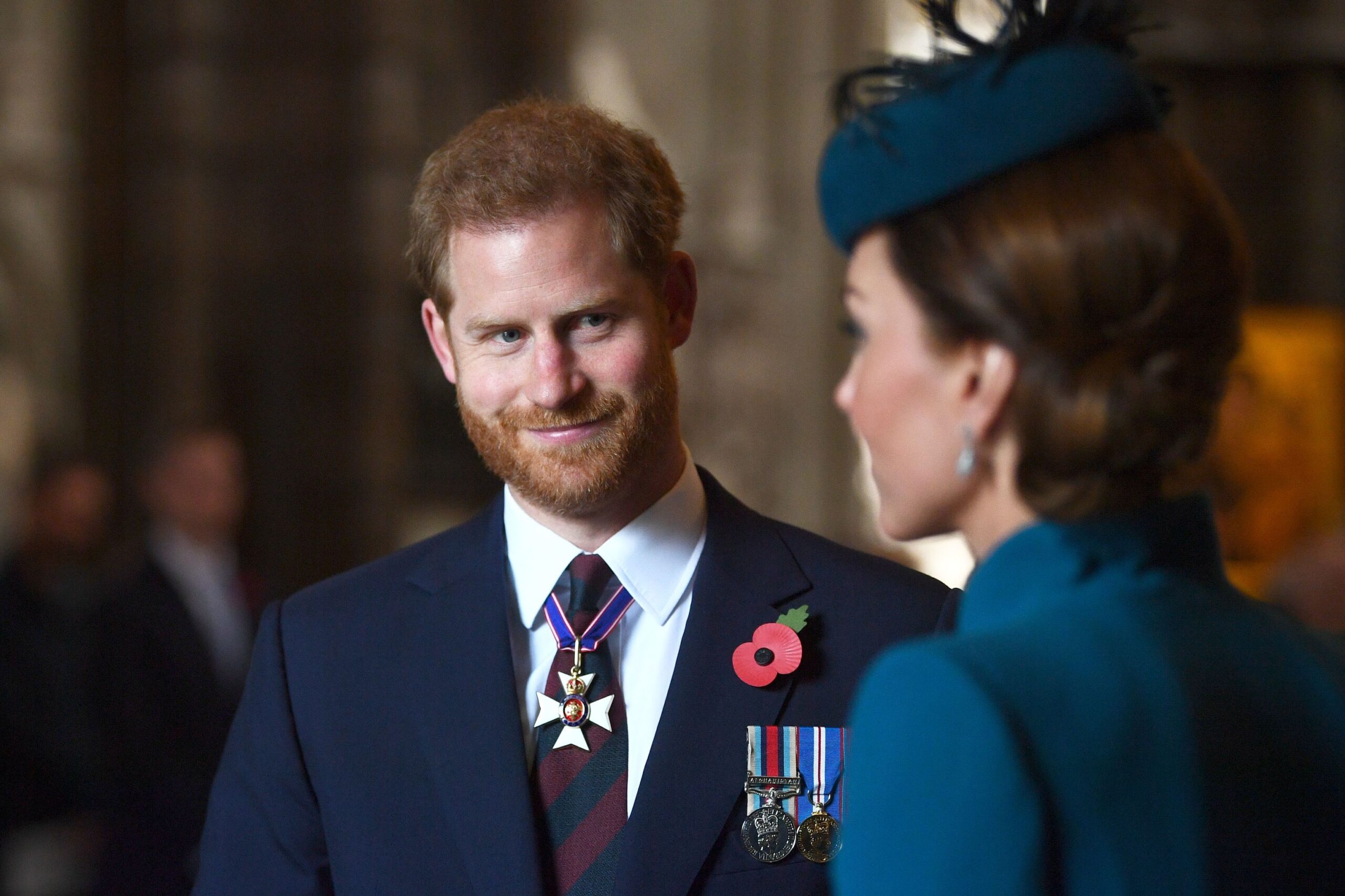 Prince Harry smiling at Kate Middleton, both wearing poppy pins.