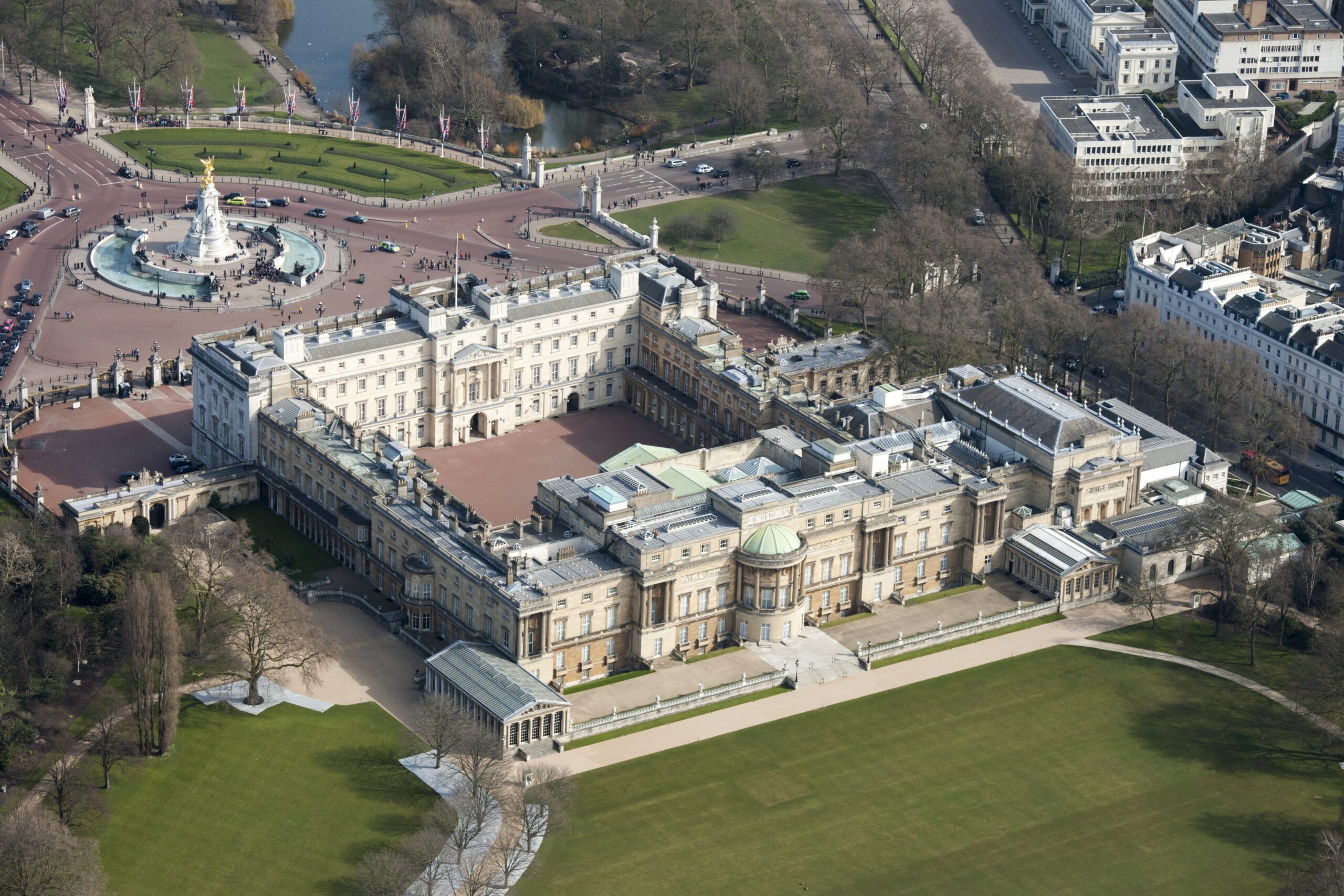 Aerial view of Buckingham Palace in Westminster, London, with the Victoria Memorial in front and green lawns surrounding it.