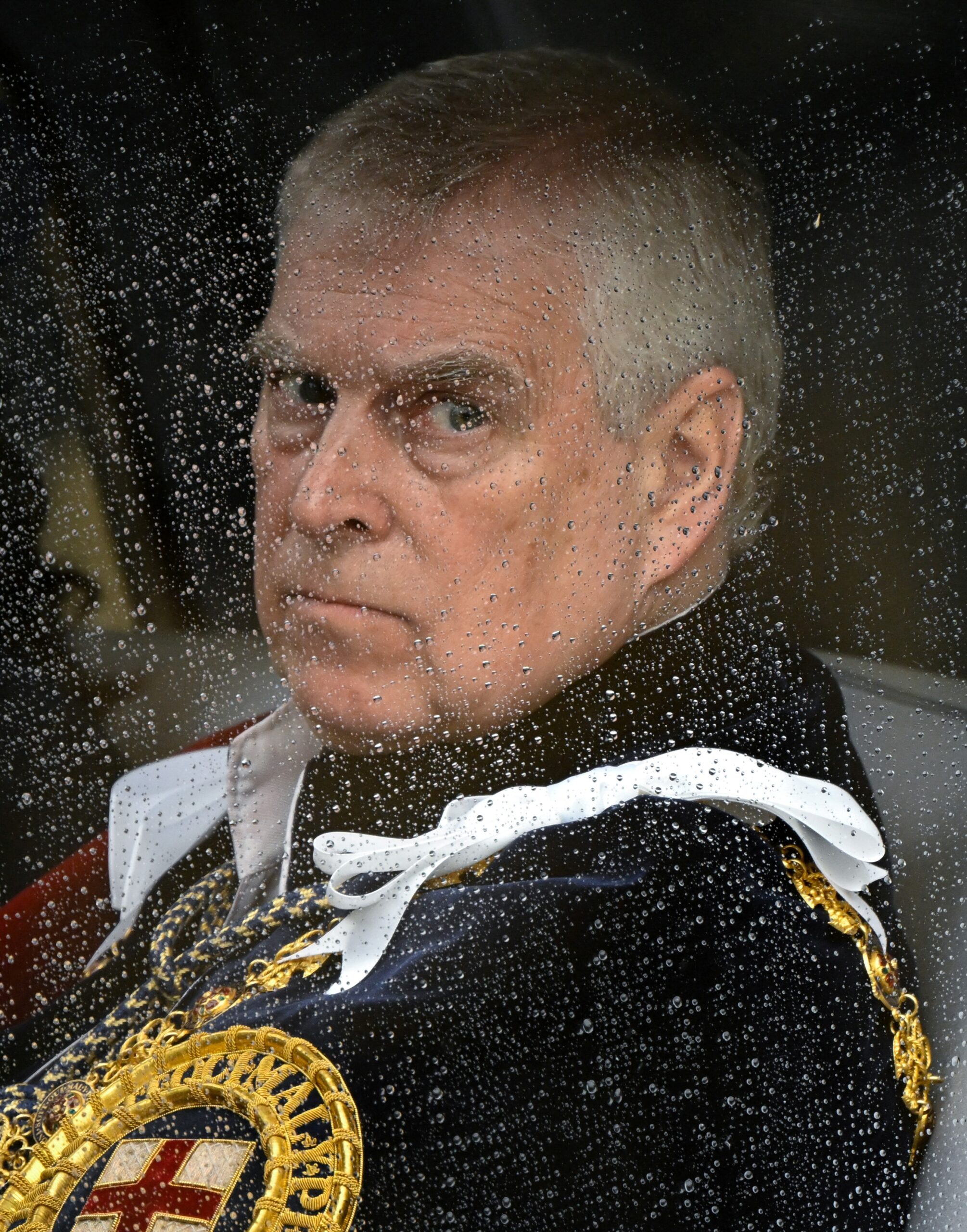 Prince Andrew looks through a rain-streaked window.