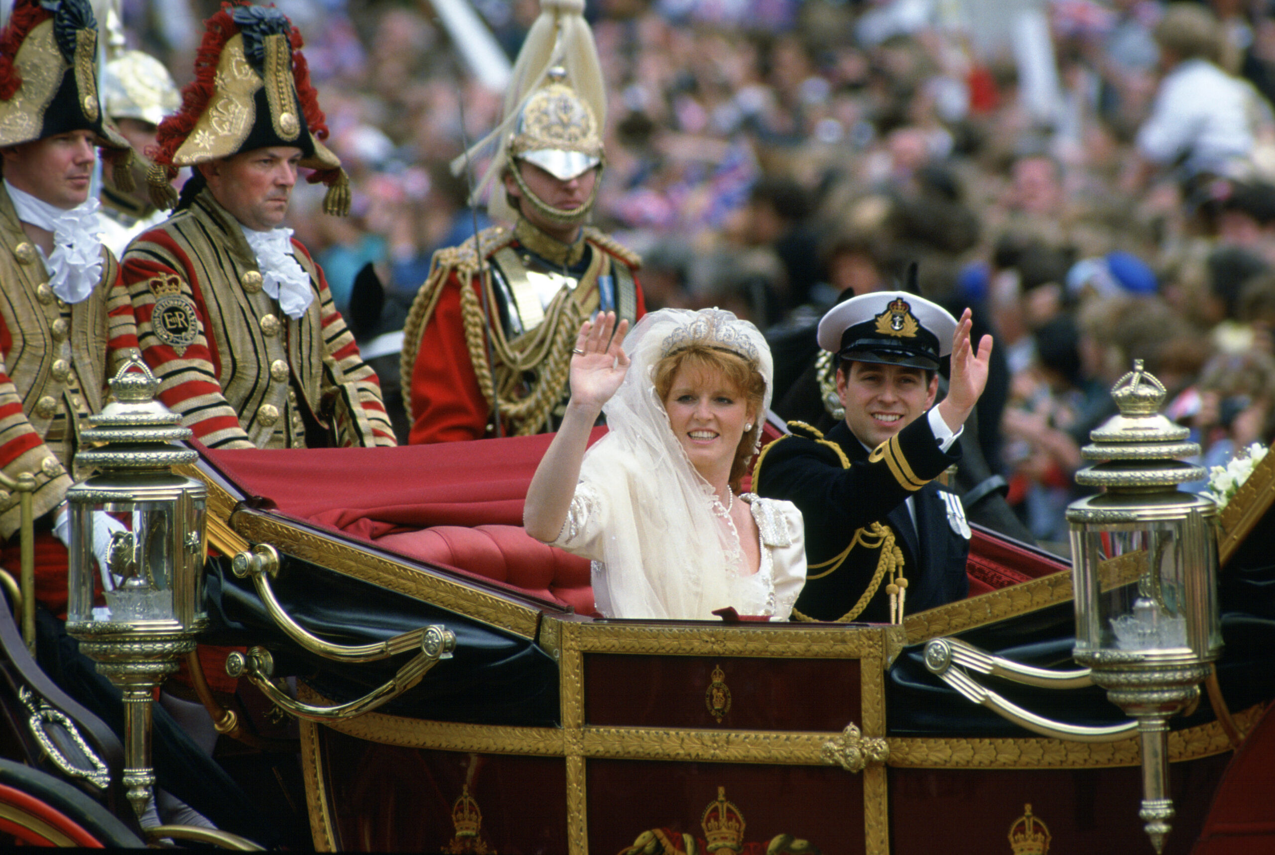 Sarah ferguson and Prince Andrew waving from a carriage at their wedding