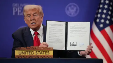 Getty Images US President Donald Trump holds up a signed memorandum of understanding between Thailand and the United States at Kuala Lumpur Convention Centre on October 26, 2025