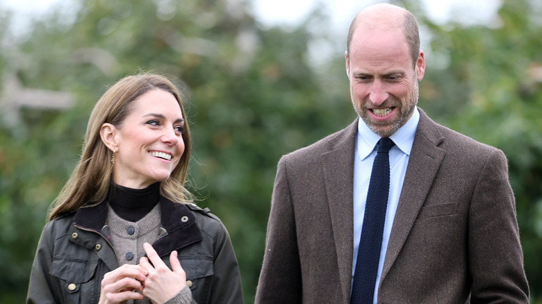 Kate Middleton and Prince William smiling and walking outdoors