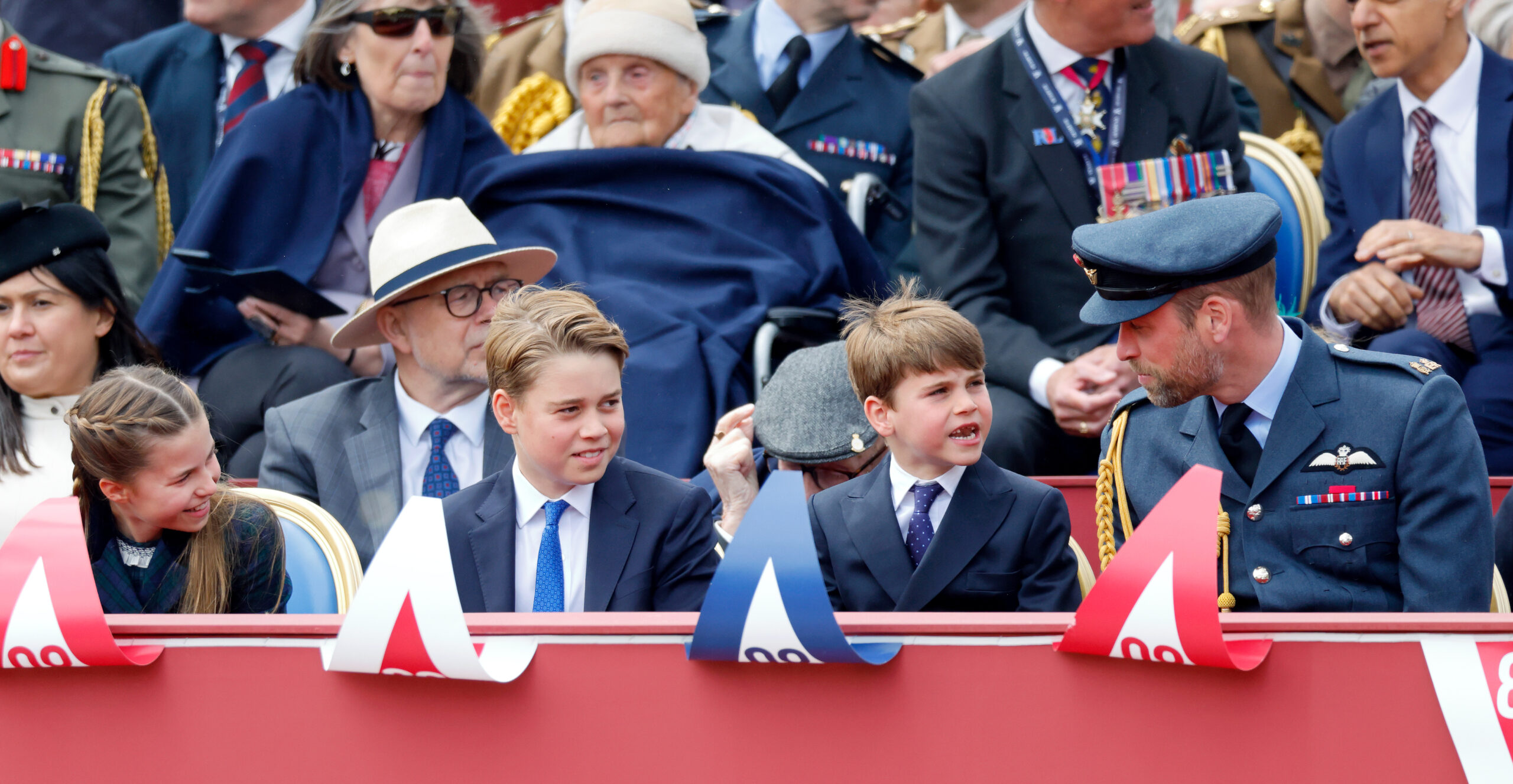 Princess Charlotte, Prince George and Prince Louis talking to Prince William sitting in a row