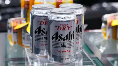 Getty Images Three silver Asahi super dry beer cans inside a factory