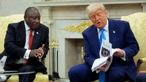 Bloomberg via Getty Images President Donald Trump show President Cyril Ramaphosa a pile of documents