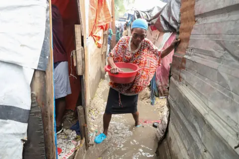 Reuters A woman carries a bowl of water as she removes water from her home following flooding in Port-au-Prince, Haiti on 29 October.