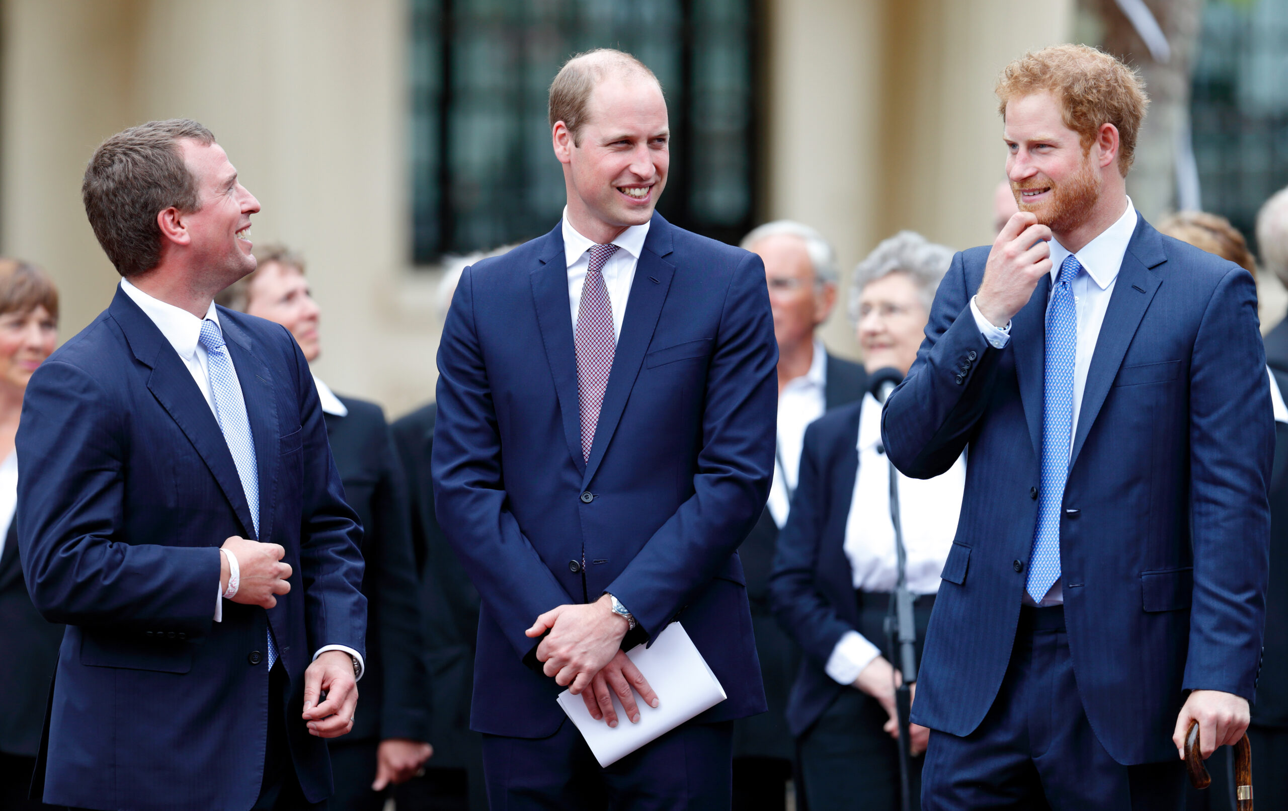Peter Phillips, Prince William and Prince Harry wearing blue suits and laughing