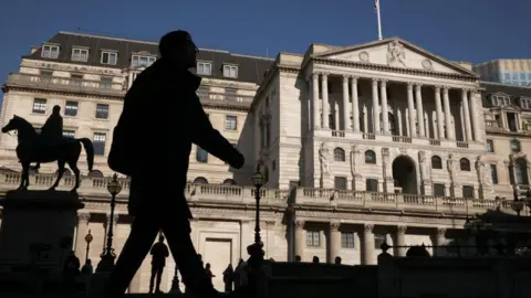 Getty Images Man in shadow walks in from of the Bank of England building