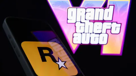 Getty Images The logo for Rockstar Games is displayed on a smartphone screen, with the logo for the upcoming game Grand Theft Auto VI shown on a backdrop behind it.