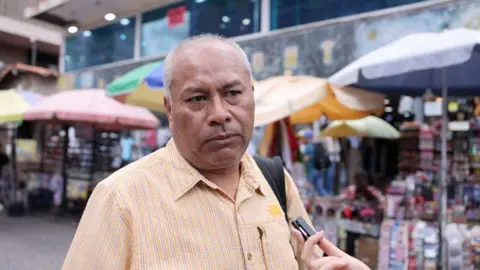 Javier Jaramillo looks towards the interviewer in front of some vendors' stalls in Caracas