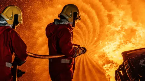 Getty Images Firefighters spray water on a fierce fire