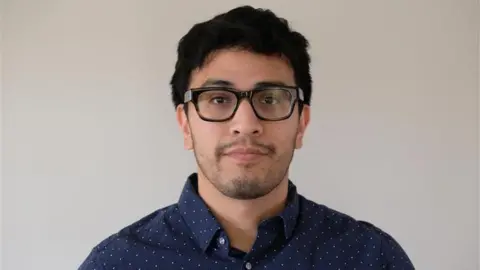 Ivan Maurizi A man wearing glasses and a blue collared shirt.