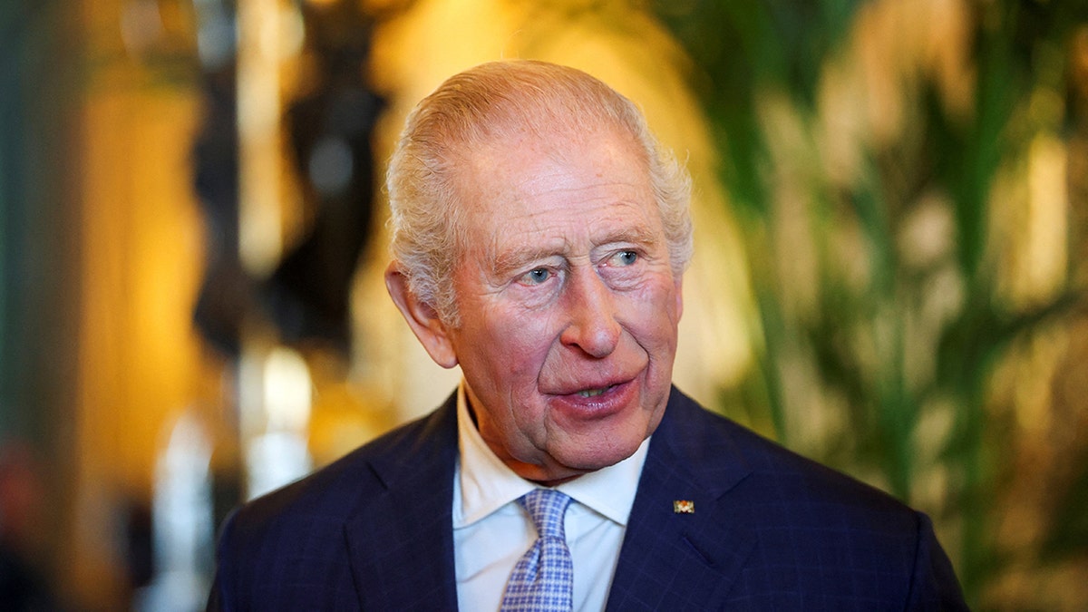 King Charles in a dark blue suit in mid-conversation.