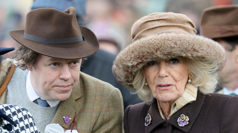 Tom Parker Bowles whispers to Queen Camilla at an outdoor event