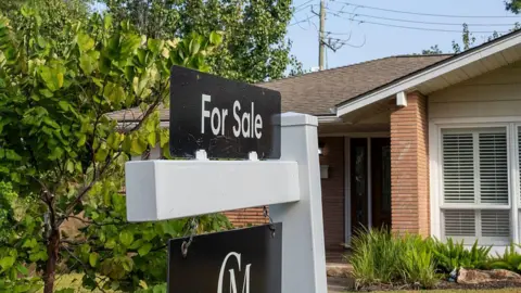 Houston Chronicle via Getty Images A for sale sign is seen in front of a house in a neighbourhood in Houston.
