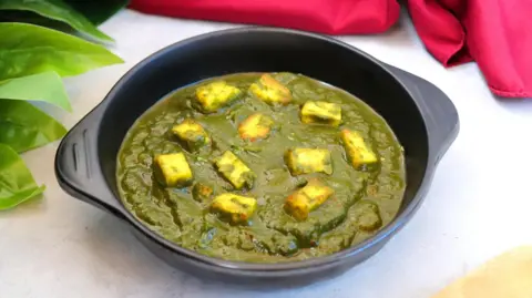 Getty Images Palak paneer is prepared using pureed spinach and cubes of cheese and is mostly eaten with naan, a type of bread, and rice
