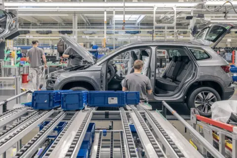 AFP via Getty Images Workers at a Volkswagen factory in Slovakia, and a car under assembly