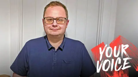 Sam Gillson Sam Gillson, wearing glasses and a blue polo shirt, with Your Voice branding on the right hand side of the picture