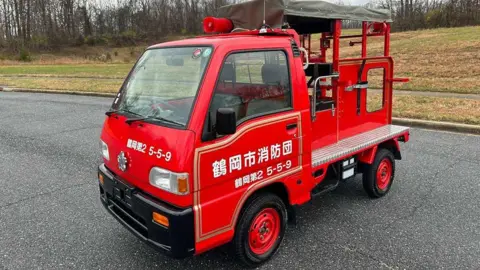 Tokyo Motors DC A picture of a Japanese mini fire truck parked on a tarmac road 
