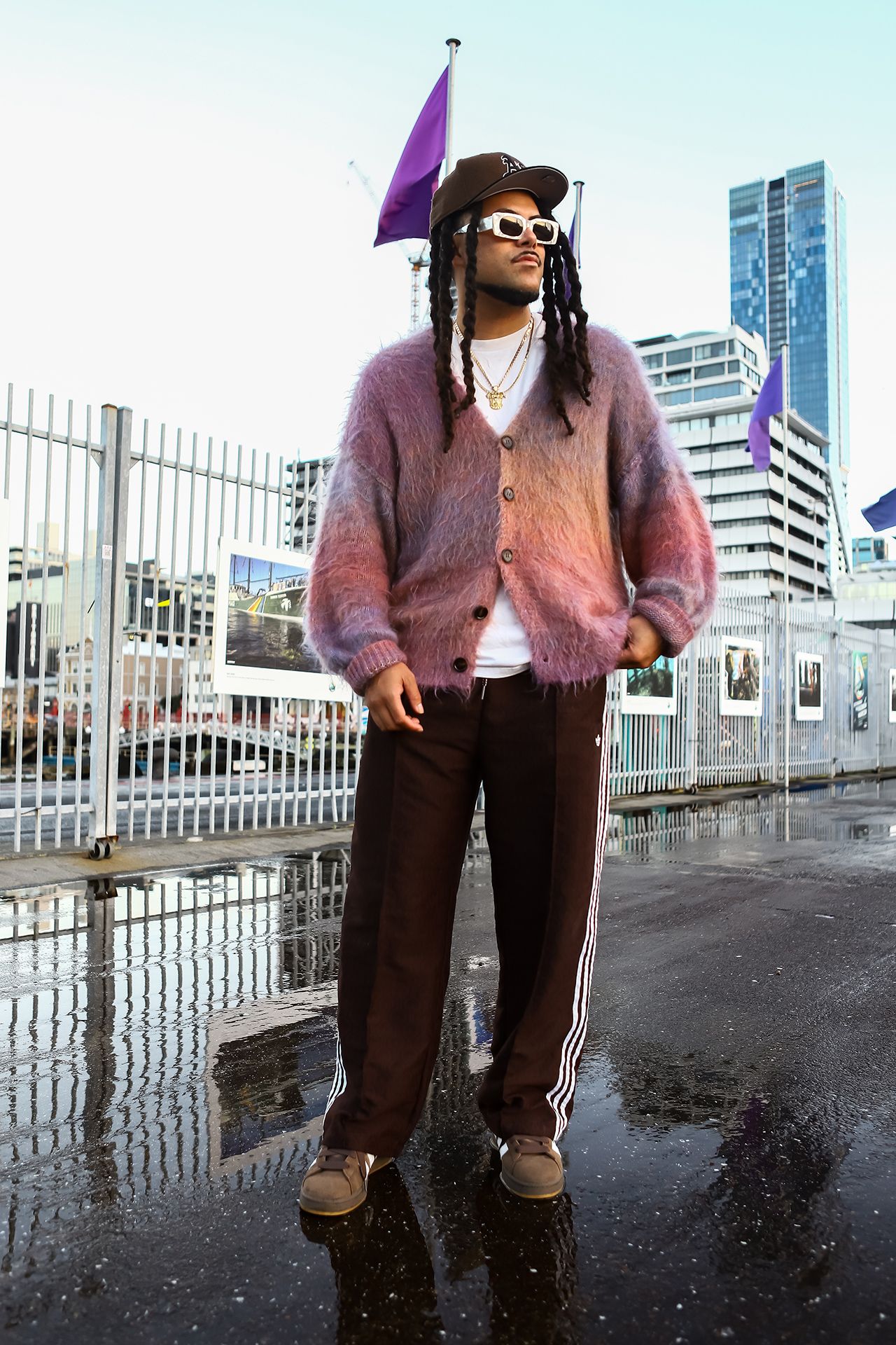 Image may contain Purple City Clothing Hat Adult Person Knitwear Sweater Footwear Shoe Coat Cap and Urban