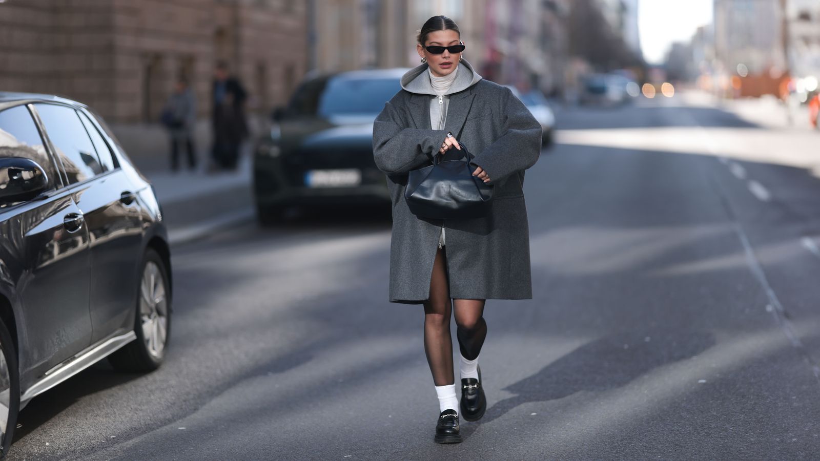 Image may contain: Pedestrian, Person, Clothing, Coat, Accessories, Bag, Handbag, Car, Transportation, Vehicle, and Footwear