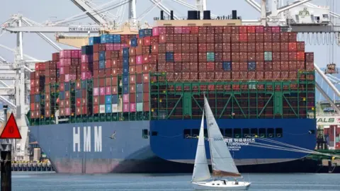 EPA/Shutterstock A sailboat sails past a container ship at the Port of Oakland in Oakland, California, USA, 14 July 2025.