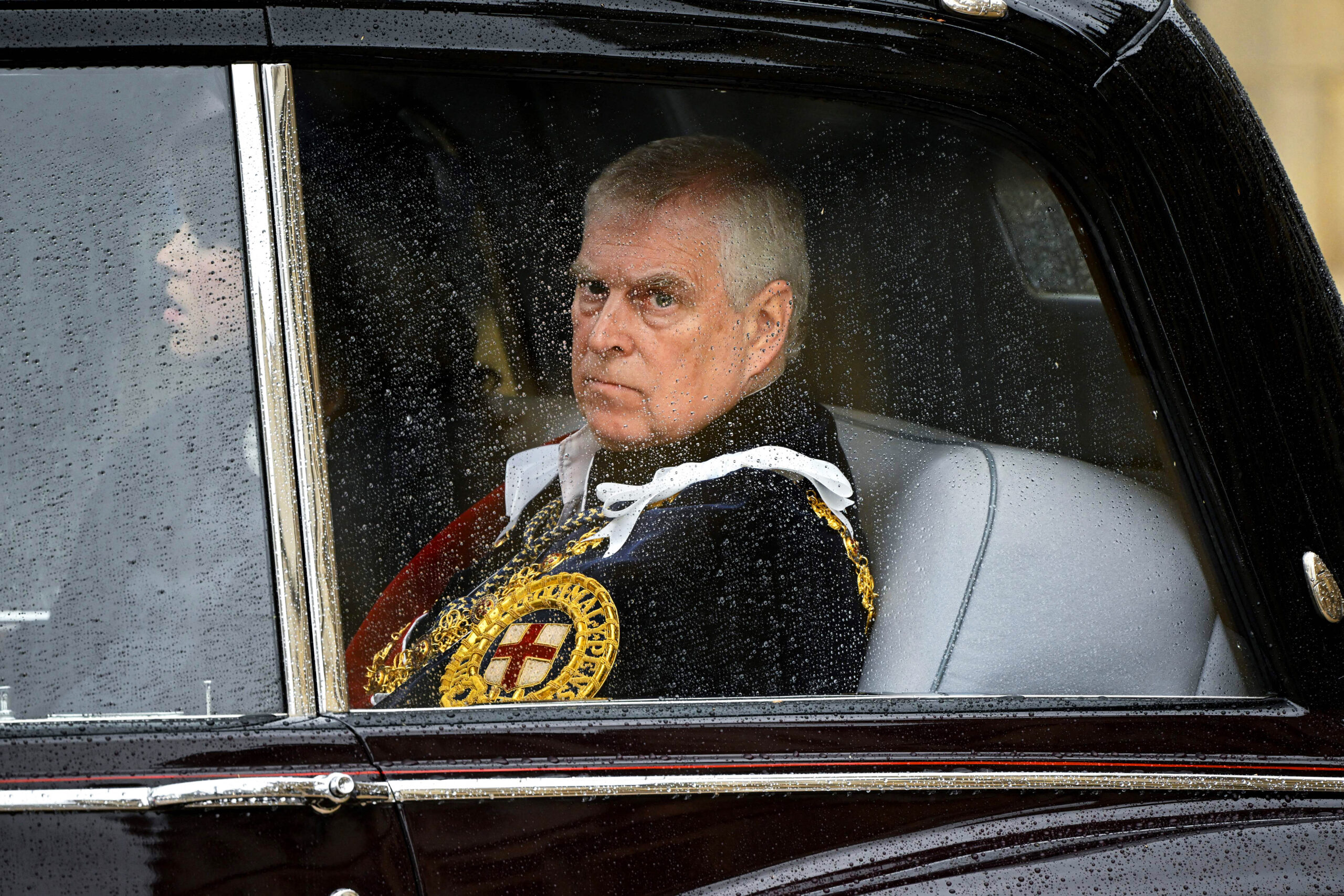 Prince Andrew in a car with rain drops on the window.