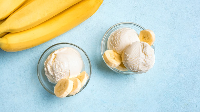 Ice cream scoops and banana slices in bowls on blue background, top view. banana ice cream