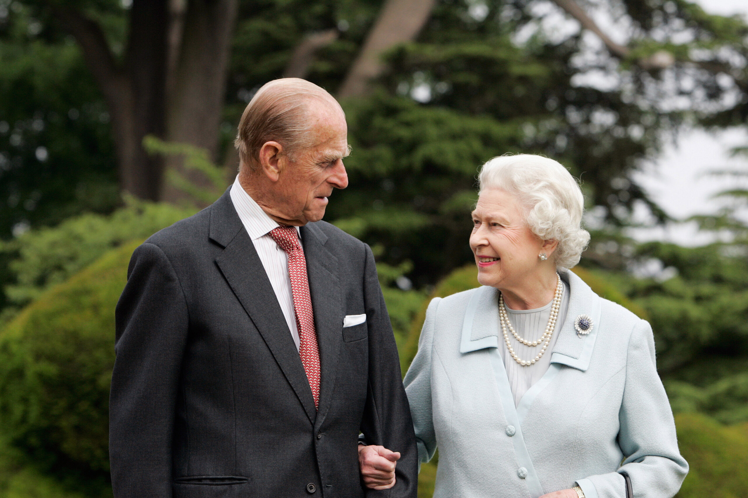 Prince Philip and Queen Elizabeth posing for a 60th anniversary photo in front of trees